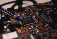 Close-up view of a circuit board with a prominent microchip labeled 'GigaPlatz 11153' and a tool for adjustment.